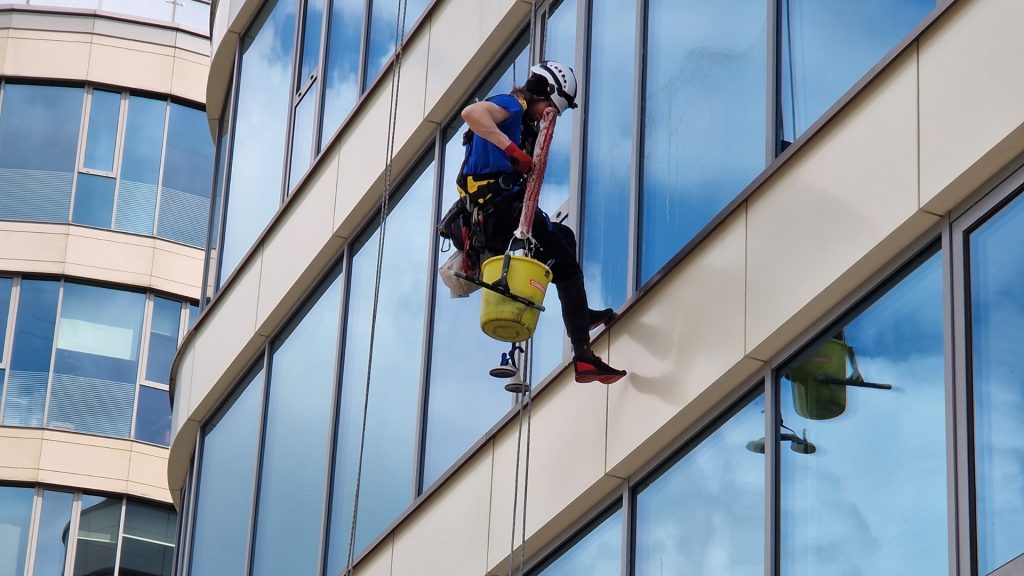 Un homme nettoie une vitre en hauteur