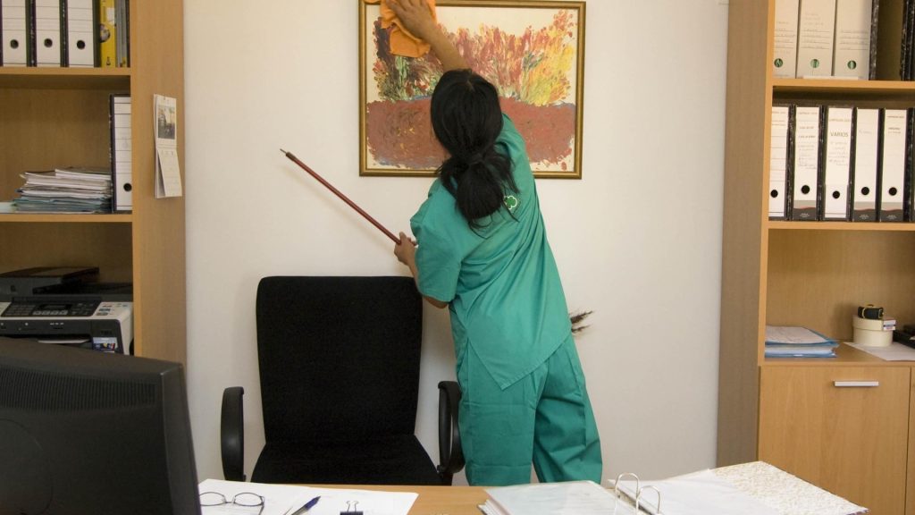 Une femme qui nettoie un cadre dans un bureau p^r